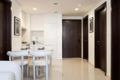a kitchen with a table and two white stools at Modern Two Bedroom Apartment with Private Balcony By HSHOME - Downtown Dubai in Dubai