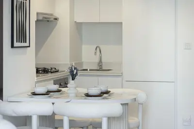 a white kitchen with a table and chairs at Modern Two Bedroom Apartment with Private Balcony By HSHOME - Downtown Dubai in Dubai
