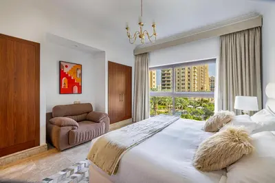 a bedroom with a large bed with a chair and a window at Fairmont North 2BR Balcony Sea View in Dubai