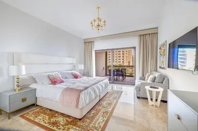 a white bedroom with a bed and a living room at Fairmont North 2BR Balcony Sea View in Dubai