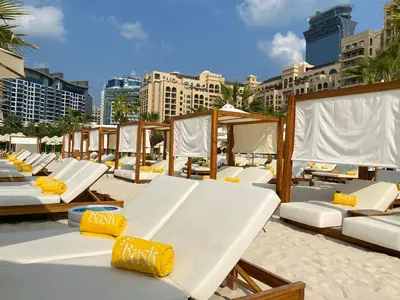 a row of beds on a beach with buildings at Fairmont North 2BR Balcony Sea View in Dubai