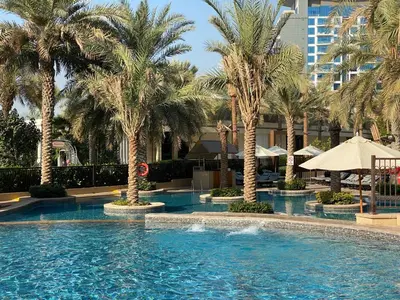a swimming pool with palm trees in a hotel at Fairmont North 2BR Balcony Sea View in Dubai