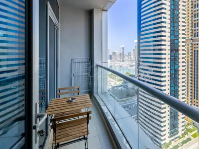 a balcony with a wooden table and a view of a city at 1BD apartment in Torch Tower, Dubai Marina in Dubai