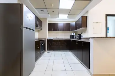 a kitchen with black cabinets and a stainless steel refrigerator at 1BD apartment in Torch Tower, Dubai Marina in Dubai