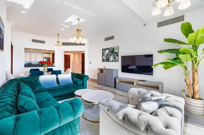 a living room with a green couch and white chairs at Fairmont North 2BR Full Sea View in Dubai
