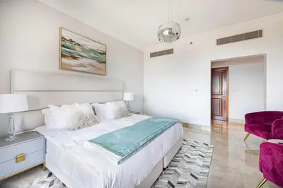a white bedroom with a bed and a purple chair at Fairmont North 2BR Full Sea View in Dubai