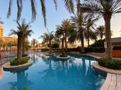 a large swimming pool with palm trees in a resort at Fairmont North 2BR Full Sea View in Dubai