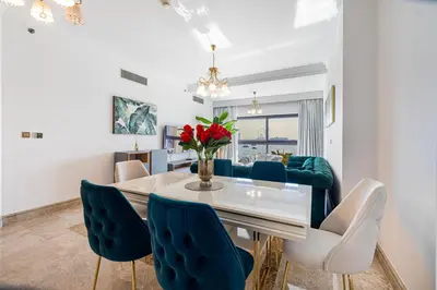 a dining room with a table and blue chairs at Fairmont North 2BR Full Sea View in Dubai