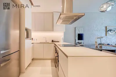 a kitchen with white cabinets and a refrigerator at Mira Holiday Homes - Lovely 2 BDR with Sea View in Dubai
