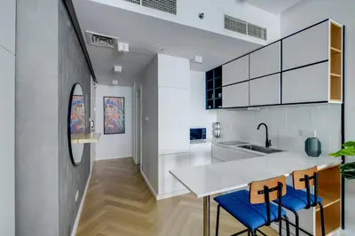 a kitchen with a white counter and blue chairs at Bright and cozy - Studio - JLT in Dubai