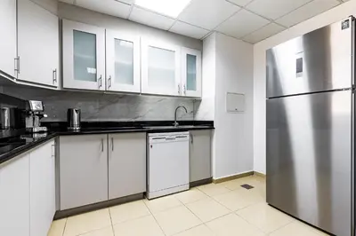 a kitchen with white cabinets and a stainless steel refrigerator at JBR Full Sea View Apartment 1 BR in Dubai