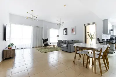 a white living room with a table and chairs at JBR Full Sea View Apartment 1 BR in Dubai
