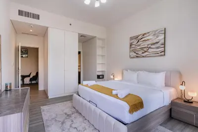 a bedroom with a large bed and a living room at Belgravia T2,JVC - 2BR Duplex Apartment - Allsopp&Allsopp in Dubai