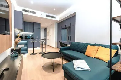 a living room with a blue couch and a kitchen at Stylish and Sleek - Studio - JLT in Dubai