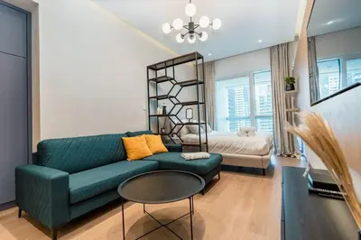 a living room with a green couch and a bed at Stylish and Sleek - Studio - JLT in Dubai