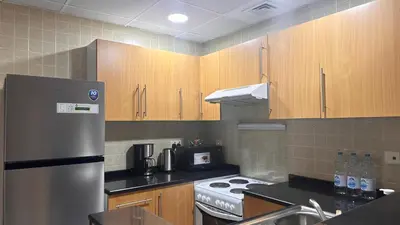 a kitchen with wooden cabinets and a stainless steel refrigerator at Spontaneous Sea View and High floor Studio Apartment in Dubai