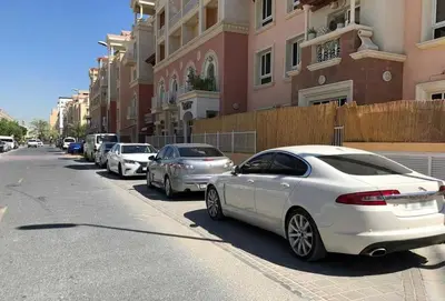 a row of cars parked on the side of a street at A chilled place JVC in Dubai