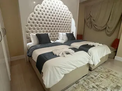 two beds in a bedroom with a large headboard at ROYAL BEACH RESIDENCES 2 in Dubai