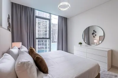 a bedroom with a white bed and a mirror at 3BDR with Maid Room I District One I Spacious and Cozy in Dubai