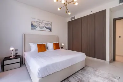 a bedroom with a white bed and a brown cabinet at 3BDR with Maid Room I District One I Spacious and Cozy in Dubai