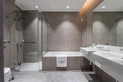 a bathroom with two sinks and a shower and a tub at 3BDR with Maid Room I District One I Spacious and Cozy in Dubai