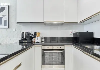 a kitchen with white cabinets and a stove top oven at bnbme - Premium 1BR Apt Balcony Pool Gym Parking Near Dubai Mall & Burj Khalifa in Dubai