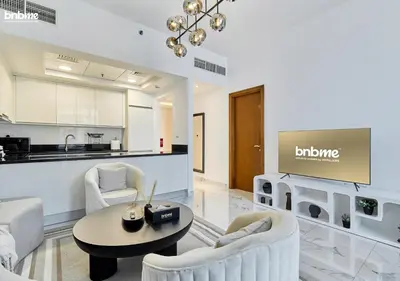 a living room with white furniture and a kitchen at bnbme - Premium 1BR Apt Balcony Pool Gym Parking Near Dubai Mall & Burj Khalifa in Dubai