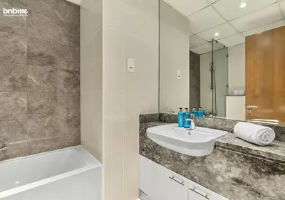 a bathroom with a sink and a tub and a mirror at bnbme - Premium 1BR Apt Balcony Pool Gym Parking Near Dubai Mall & Burj Khalifa in Dubai