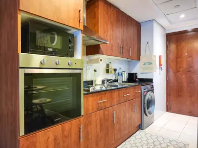 a kitchen with wooden cabinets and a microwave at Rustic Elegance By The Lake Studio Cabin In Jlt in Dubai