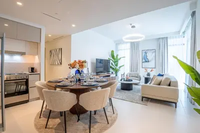 a kitchen and living room with a table and chairs at Veluxa - Luxe 2Bed with Private Beach in Dubai