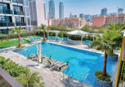an overhead view of a swimming pool with palm trees and buildings at HAVN - Studio Apartment in Chaimaa Avenue, JVC in Dubai