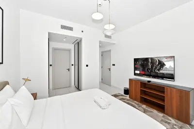 a white bedroom with a bed with a flat screen tv at Seascape Sanctuary - 3 and a Half BR Beachfront Bliss - Marina Vista Tower 1 in Dubai