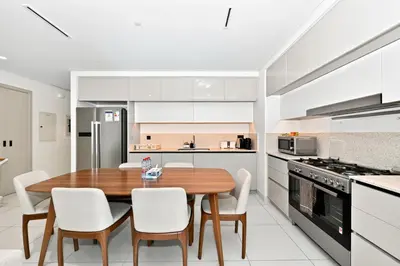 a kitchen and dining room with a wooden table and chairs at Seascape Sanctuary - 3 and a Half BR Beachfront Bliss - Marina Vista Tower 1 in Dubai