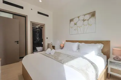 a bedroom with a large white bed with white pillows at Chic 1BR in JVC with Balcony, Near Mall & Parks in Dubai