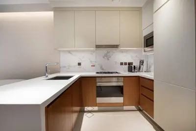 a kitchen with white counters and wooden cabinets at Luxurious stay in Downtown Dubai in Dubai