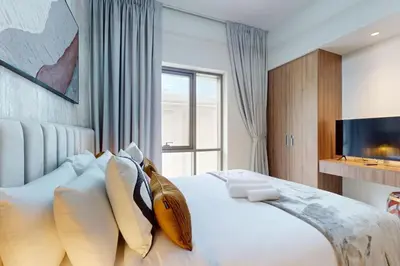 a bedroom with a large bed with pillows and a tv at Vida Residences at Creek Beach - Light Two Bedroom in Dubai
