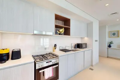 a kitchen with white cabinets and a stove top oven at Vida Residences at Creek Beach - Light Two Bedroom in Dubai