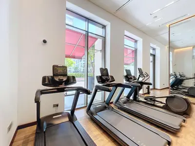 a gym with treadmills and ellipticals in a room with windows at Vida Residences at Creek Beach - Light Two Bedroom in Dubai