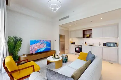 a living room with yellow and white furniture and a kitchen at Vida Residences at Creek Beach - Light Two Bedroom in Dubai