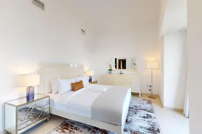a white bedroom with a large bed and a table at Cayan Tower - Smart One Bedroom Loft on High Floor in Dubai