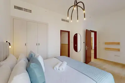 a bedroom with a large white bed with blue pillows at Vacationer I Premium 1 Bed I Steps to JBR Beach & Nightlife I Bahar 6 Tower in Dubai