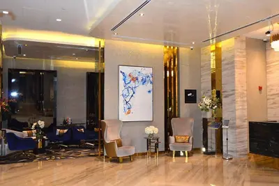 a lobby with chairs and tables and a painting on the wall at Dazzling Studio Apartment in Business Bay l City View in Dubai