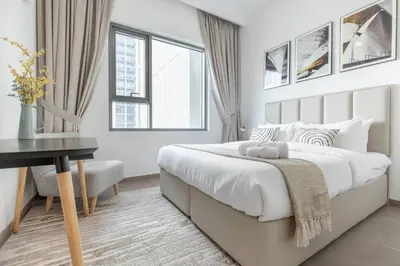 a white bedroom with a large bed and a desk at 1BR Apartment in Park Heights 2 Dubai Hills in Dubai