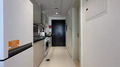 a kitchen with white cabinets and a black door at EasyGo - Carson Tower C Damac Hills Studio in Dubai