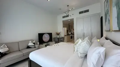 a bedroom with a white bed and a couch at EasyGo - Carson Tower C Damac Hills Studio in Dubai