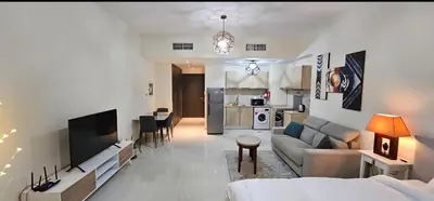 a living room with a couch and a tv and a kitchen at Luxury Studio Apartment By DownTown in Dubai