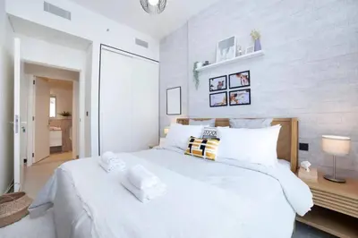 a white bedroom with a large white bed with pillows at Dubai Hills Collective Tower 2 in Dubai