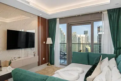 a living room with a green couch and a large window at Super High Infinity Pool & Stunning Burj Khalifa View, 3-Bedroom Apartment at Paramount Hotel Midtown in Dubai