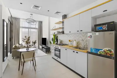 a kitchen with white cabinets and a table in a room at Silkhaus Chic 1BDR in Exclusive Neighbourhood in Dubai
