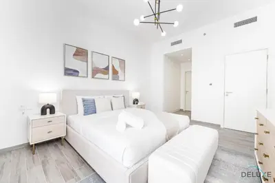 a white bedroom with a white bed and a couch at Lovely 2BR at Belgravia Square, JVC by Deluxe Holiday Homes in Dubai